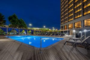 Hotel Preston Nashville Airport reviews highlight the outdoor pool at night with cabanas, bar area, and relaxing guest atmosphere